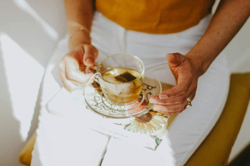 A serene scene of a person enjoying herbal tea while holding a book on a sunny day.